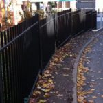 Commercial steel fencing surrounding a building situated next to a road.