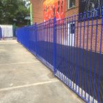 Blue bespoke railings stand in front of a commercial building.