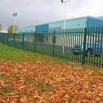 Green steel palisade fencing installed around a car park. Commercial fencing securely protects cars inside the car park.