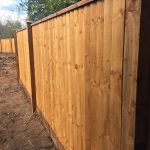 Pressure treated timber posts supporting wooden fence panels surrounding a empty area.